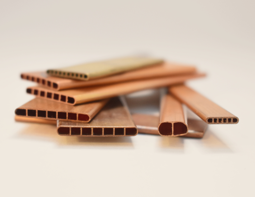 neatly arranged stack of copper extruded tube with diferent profiles